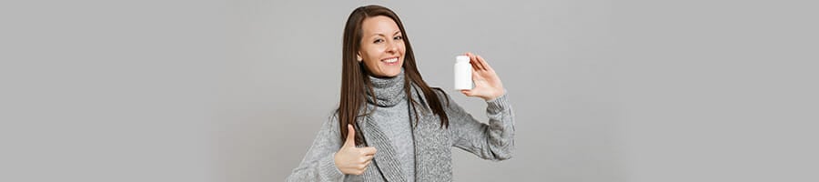woman holding up a bottle pill and her thumbs up