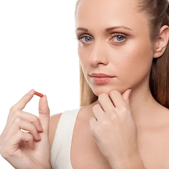 woman thinking while holding a pill