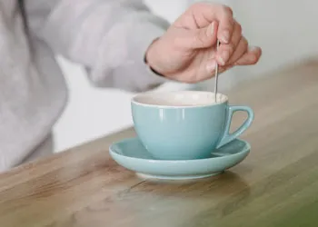 woman using a spoon to mix a mug drink