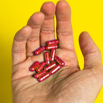 stack of red pills in a person's hand