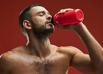 shirtless man drinking from a jug