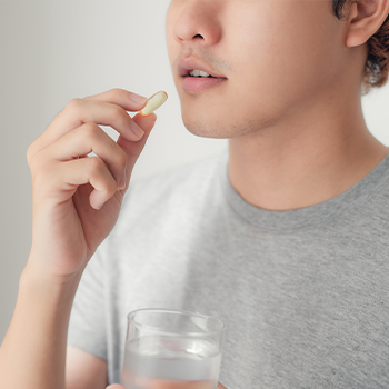 man holding a pill near his mouth