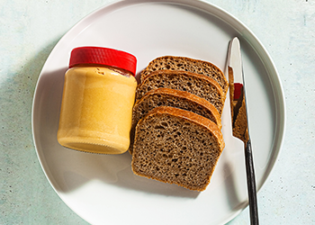 plate with peanut butter jar, slices of bread, and a knife