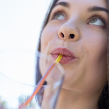 mouth view of a woman drinking from a plastic straw