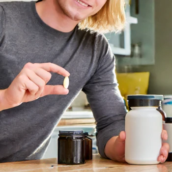 Man holding a container of supplement and a tablet