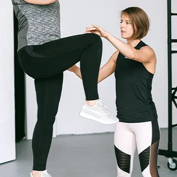 A coach teaching her student with one leg workout