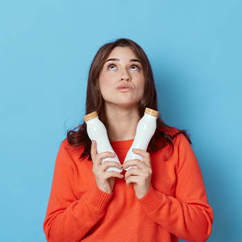 woman thinking while holding two bottles