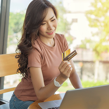 Woman using her laptop while holding a credit card