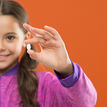 female kid holding up her vitamins