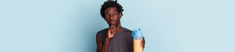 man holding up a protein drink thinking