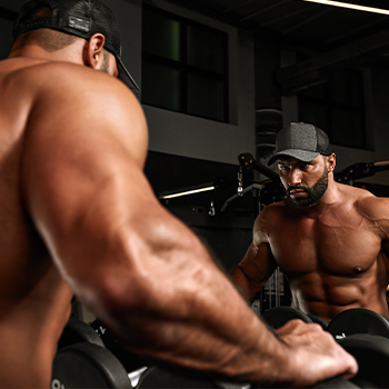 man checking himself in the mirror during a muscle pump