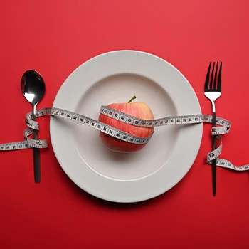 apple, fork, spoon, tape measure on plate