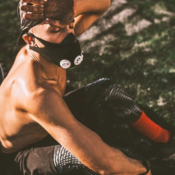 A lean man out of breath sitting on the ground