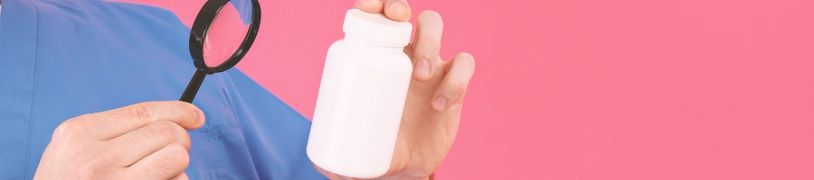 Someone looking at a pill bottle with a magnifying glass