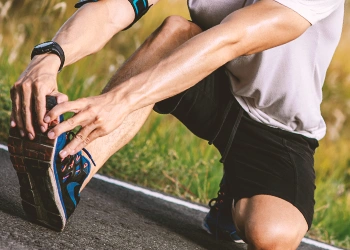 A man stretching his foot on the road