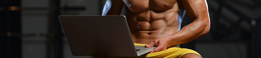 Muscular shirtless person using a laptop