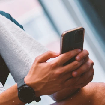 A man in the gym using a smartphone to search for the prices of Gorilla Mode