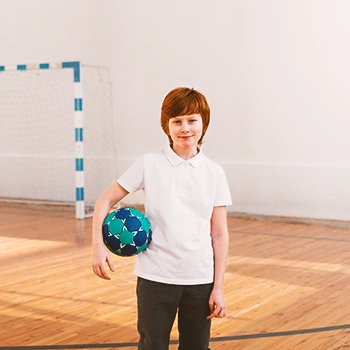 A boy holding a ball in a gym
