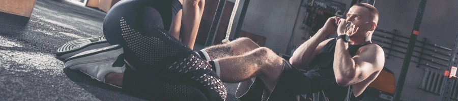 A man in the gym exercising with a woman