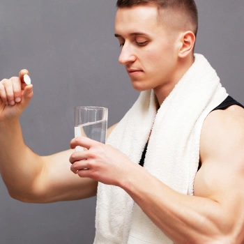 Man holding a pill and a glass of water