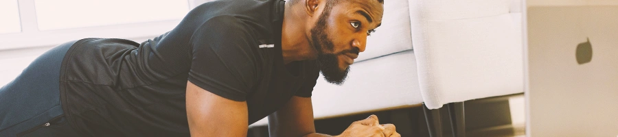 A man planking in front of a laptop