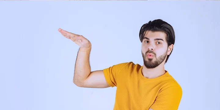 Man in yellow shirt measuring height while looking at camera