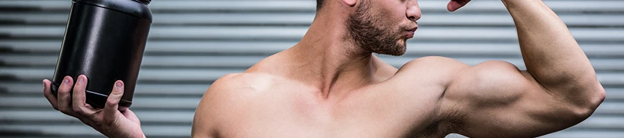 Holding a supplement container while kissing his biceps