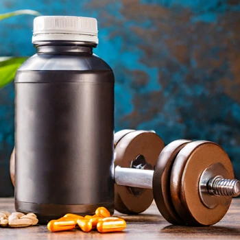 pills outside of a container and a dumbbell