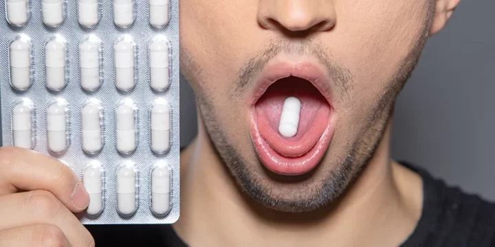 Holding pills, opening mouth with pill inside