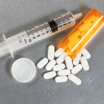 Top view of syringe and white pills