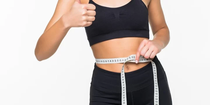 Woman giving thumbs up while measuring waist