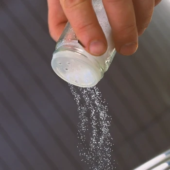 A person pouring salt from a shaker