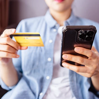 A woman holding a smartphone and a credit card to buy Alpha Lean 7