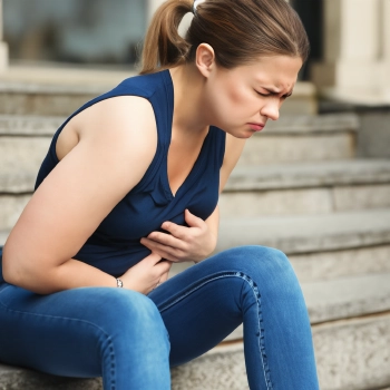 A woman sitting on a stair feeling nauseous