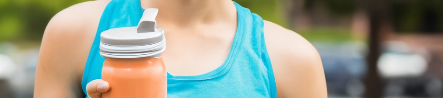 A woman holding a protein shake outside