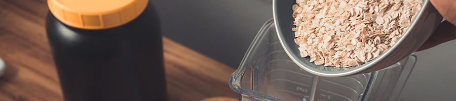 Pouring oatmeal inside a blender with supplement container background