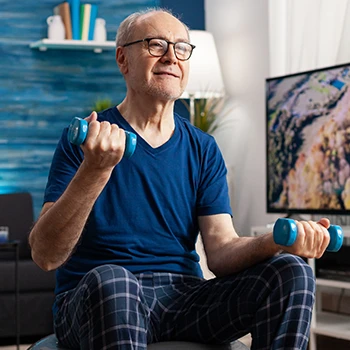 An old person using light dumb bells while sitting