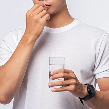 A man drinking a supplement pill