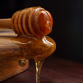 Dripping honey dipper on wood