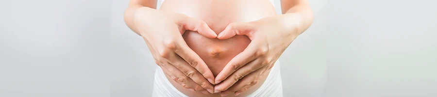 Forming a heart on her pregnant stomach