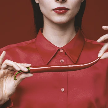 A person holding up a chili pepper