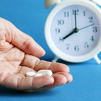 Holding pills with clock in the background