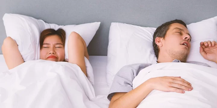 A person sleeping with a person beside him annoyed from the snoring