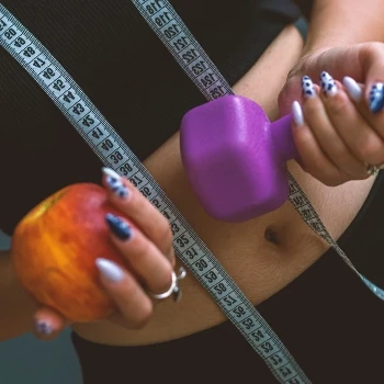 Woman holding an apple and a dumbbell