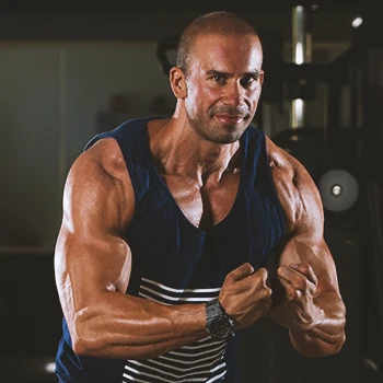 A muscular male flexing biceps in the gym