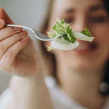 Close up image of a woman giving a spoonful of green food