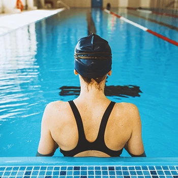 A woman in a swimming pool with her back turned around the camera