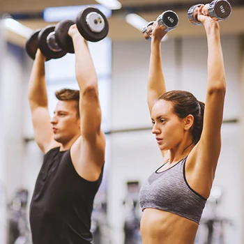Two people burning fat in the gym by lifting weights
