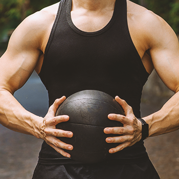 A buff person holding an exercise ball