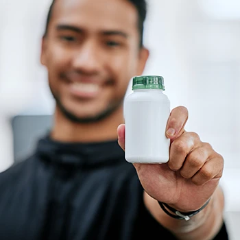 Man holding out a supplement bottle focused on camera